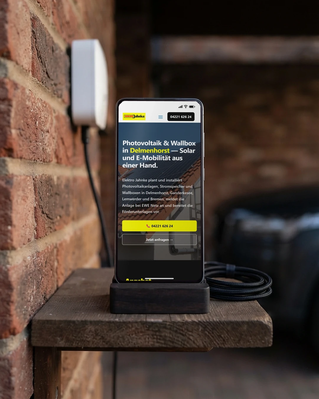 Wallbox-Seite von Elektro Jahnke am Handy im Carport neben der Wallbox: Webdesign für Elektriker nach Anliegen