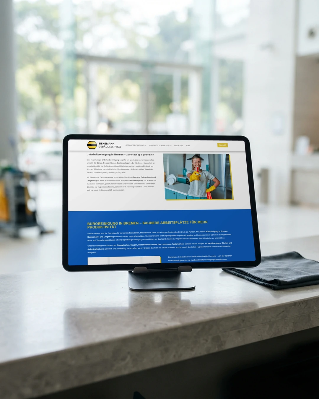 Website für Reinigungsfirmen: Unterhaltsreinigung am Tablet Seite Unterhaltsreinigung von Bienemann auf dem Tablet am Empfang eines Bürohauses: Website für Reinigungsfirmen