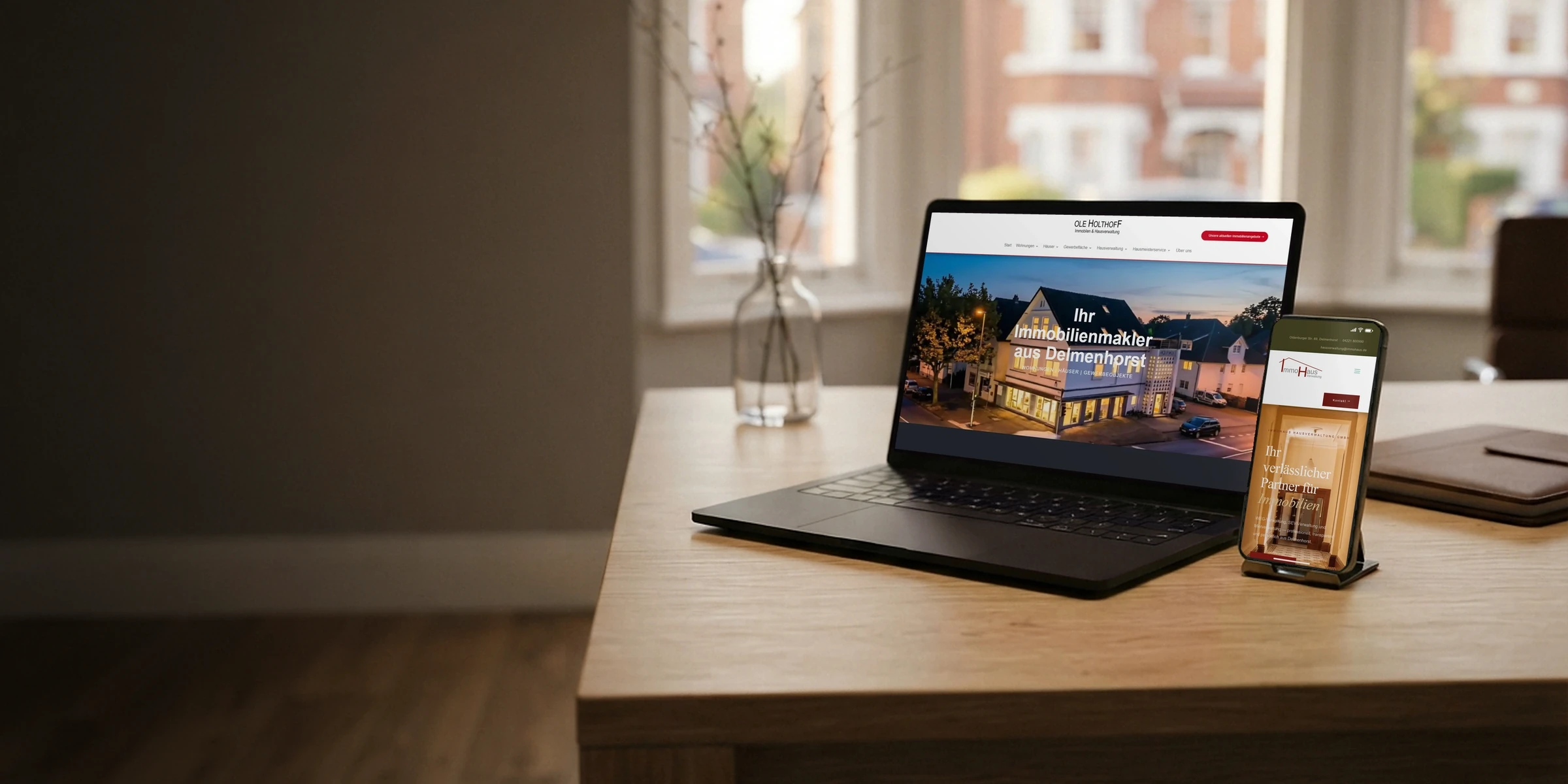 Laptop und Handy mit den Webseiten eines Maklerbüros und einer Hausverwaltung im Büro: Website für Immobilienmakler
