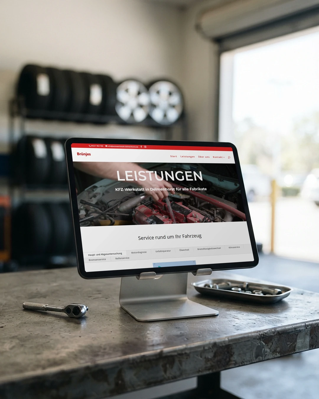 Leistungsseite von Auto Brünjes auf dem Tablet an der Werkbank: professionelle Website-Erstellung für Kfz-Werkstätten