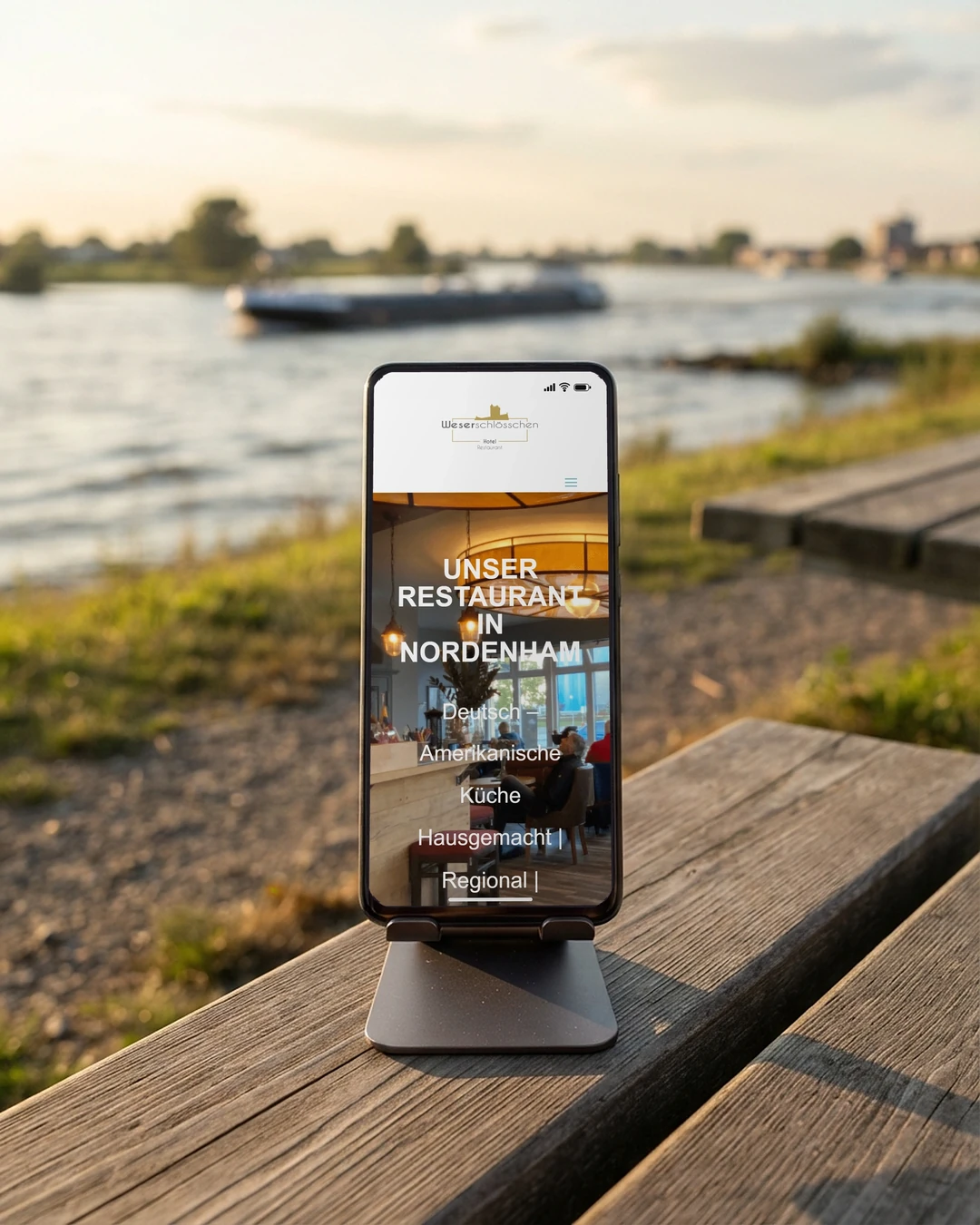 Website erstellen lassen in Nordenham: Weserschlösschen Restaurantseite vom Weserschlösschen am Handy auf dem Weserdeich: Website erstellen lassen in Nordenham