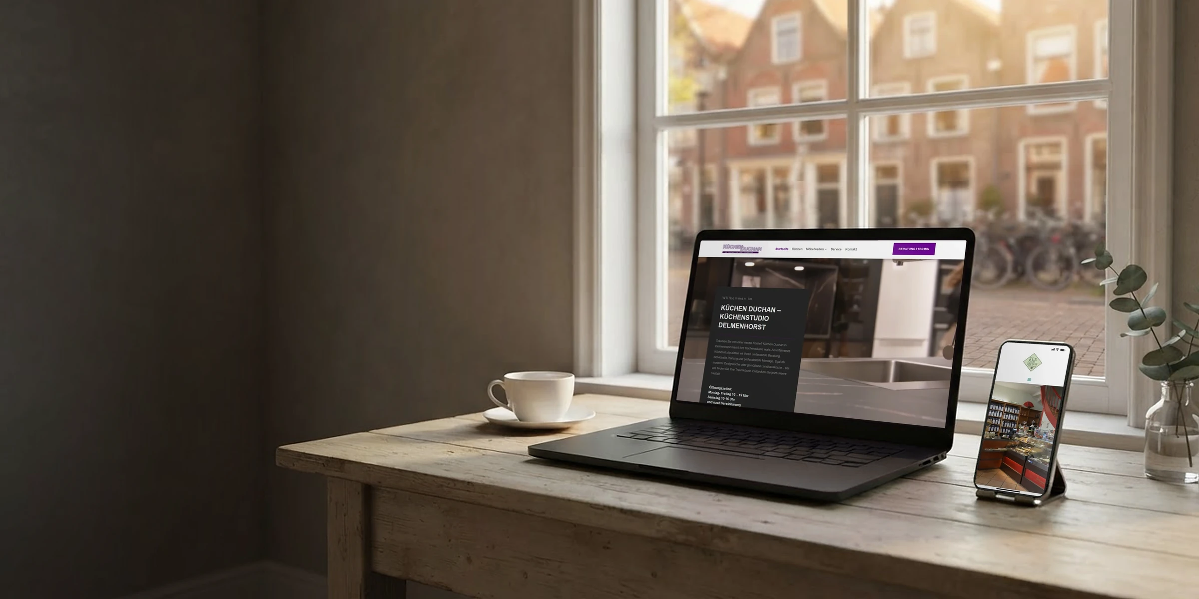 Laptop und Handy mit Webseiten eines Küchenstudios und eines Teefachgeschäfts am Altbaufenster: Webdesign Oldenburg
